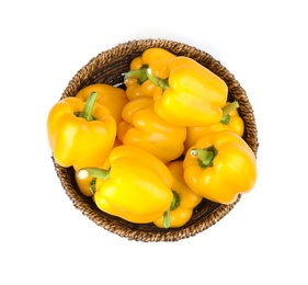 Wicker bowl of ripe yellow bell peppers isolated on white, top view