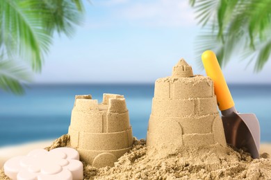 Sand castles with toys on ocean beach, closeup. Outdoor play