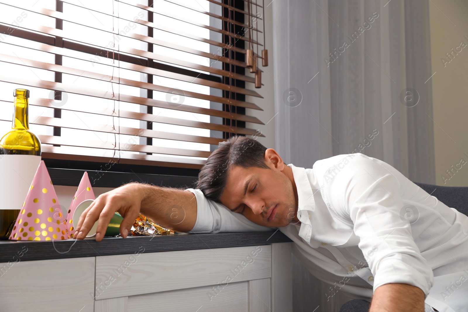 Photo of Man sleeping near window in messy room after party