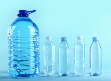 Photo of Large and small bottles with pure water on color background