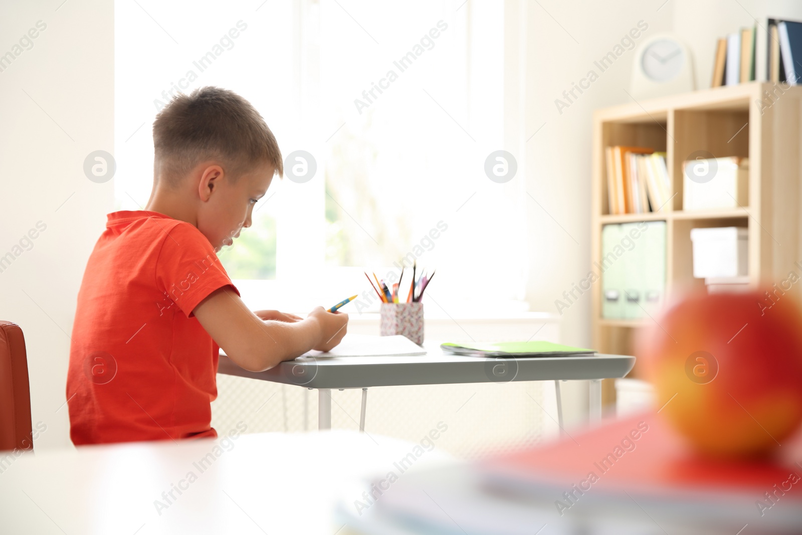 Photo of Cute little child doing assignment at desk in classroom. Elementary school