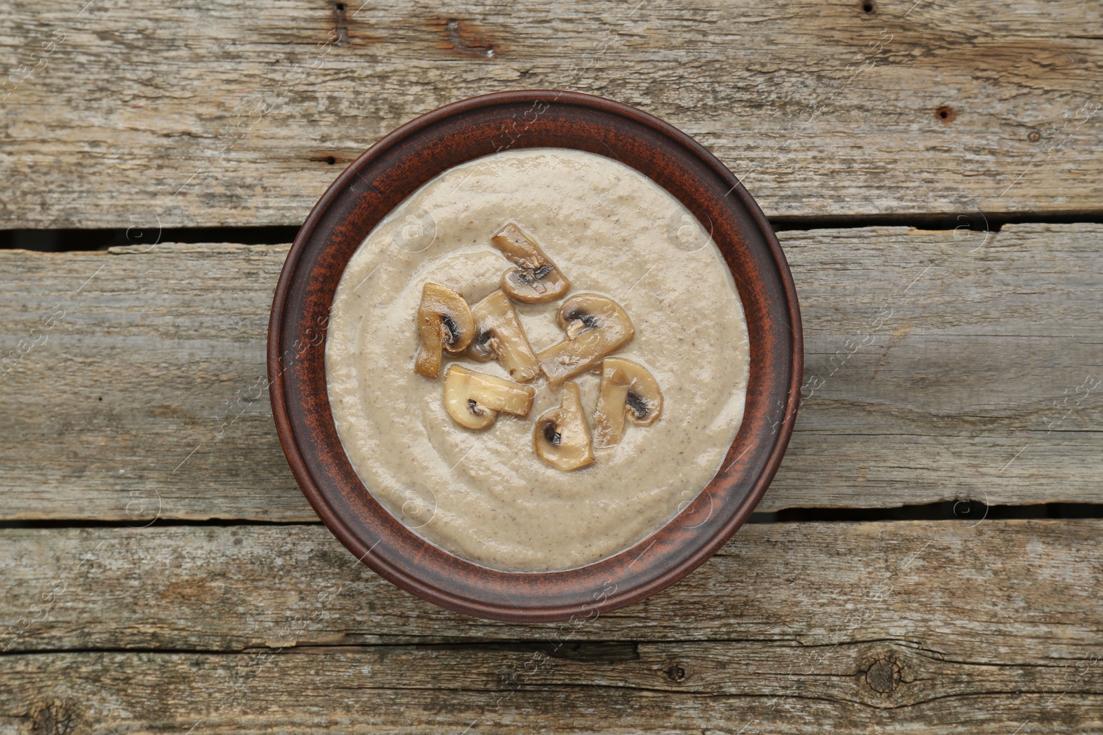 Photo of Delicious mushroom cream soup on wooden table, top view