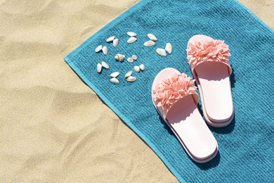 Photo of Towel, seashells and flip flops on sand, above view with space for text. Beach accessories