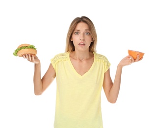 Photo of Young woman holding burger and grapefruit on white background. Choice between diet and unhealthy food