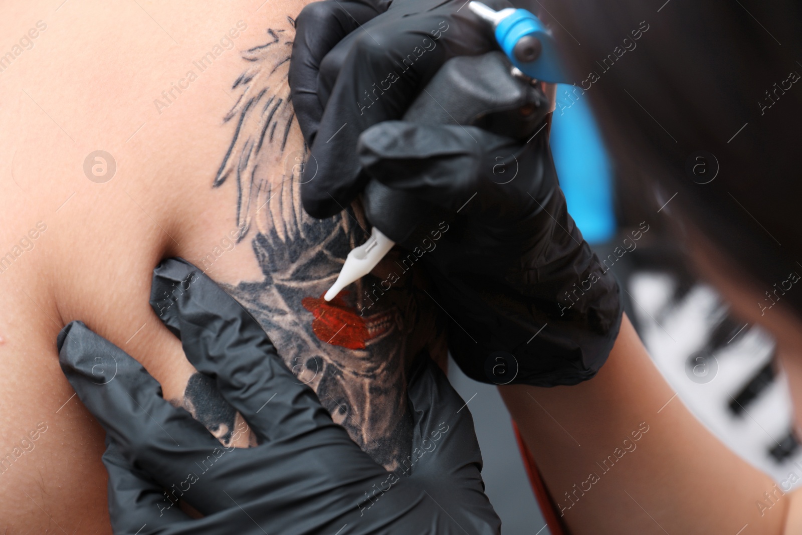 Photo of Professional artist making tattoo in salon, closeup