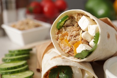 Photo of Delicious tortilla wraps with tuna, cheese and vegetables, closeup