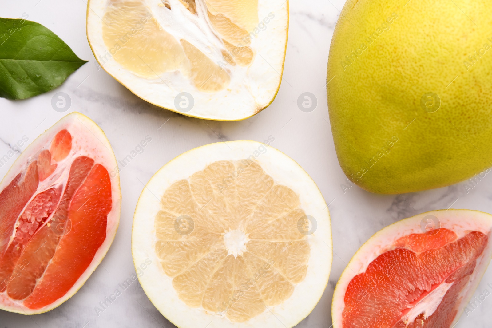 Photo of Different sorts of tasty pomelo fruits on white marble table, flat lay