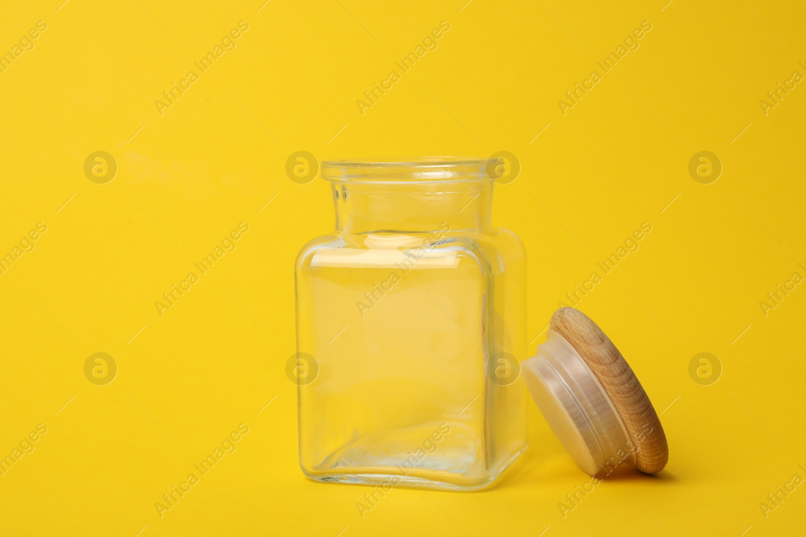 Photo of Open empty glass jar on yellow background