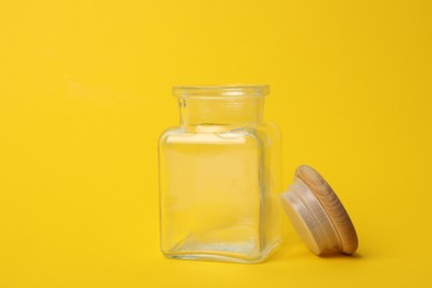 Photo of Open empty glass jar on yellow background