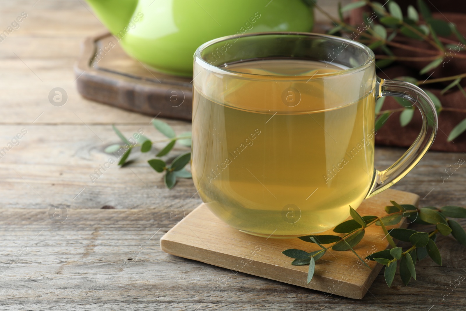 Photo of Glass cup of aromatic eucalyptus tea on wooden table, closeup. Space for text