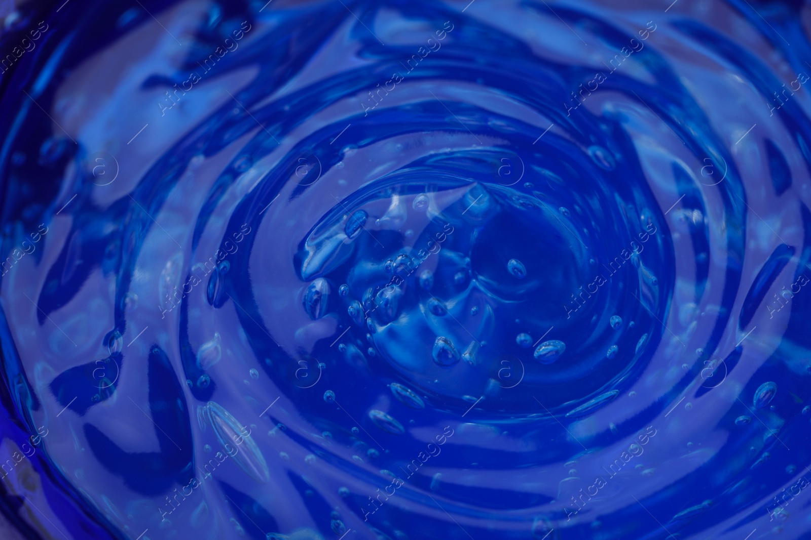 Photo of Pure transparent cosmetic gel on blue background, closeup