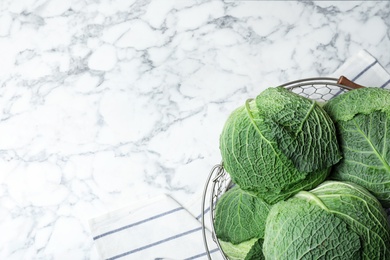 Photo of Basket with savoy cabbage and space for text on marble background, top view