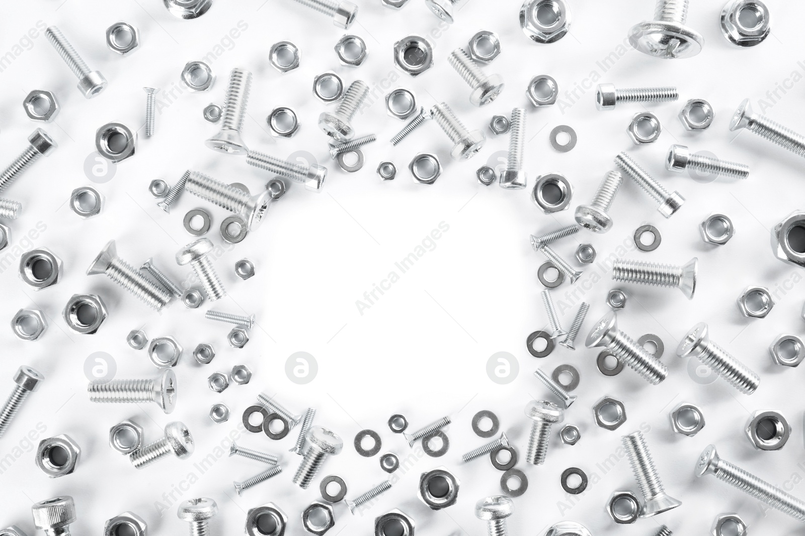 Photo of Frame of different metal bolts and nuts on white background, top view. Space for text