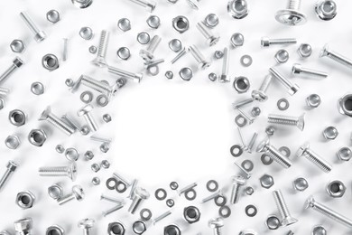 Photo of Frame of different metal bolts and nuts on white background, top view. Space for text