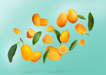 Image of Delicious fresh kumquats and green leaves falling on color background