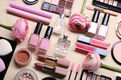 Photo of Flat lay composition with different makeup products and beautiful spring flowers on beige background