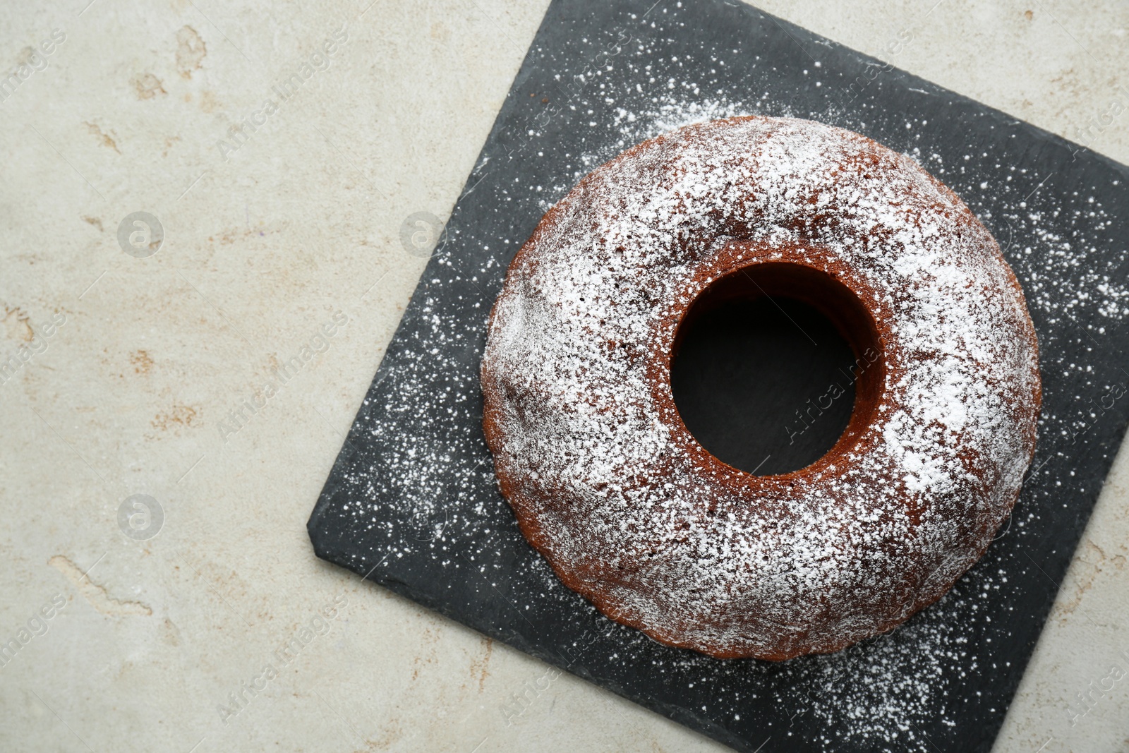 Photo of Delicious homemade yogurt cake with powdered sugar on gray table, top view. Space for text