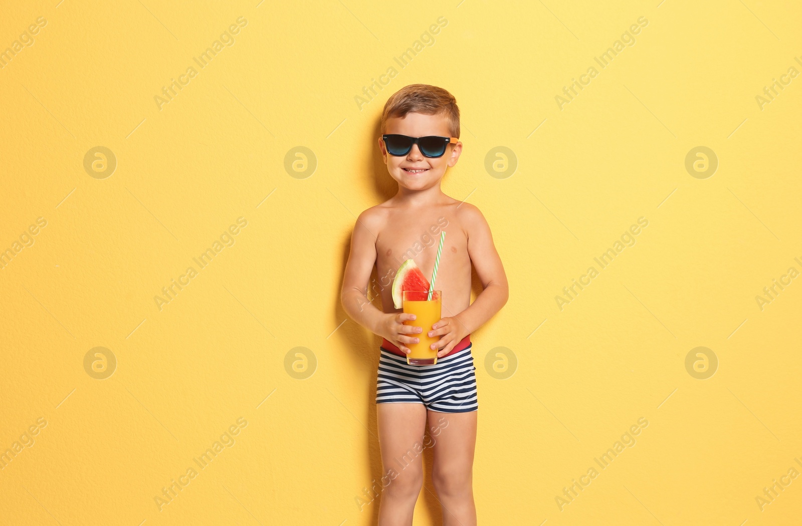 Photo of Cute little boy with glass of cocktail on color background