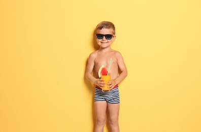 Cute little boy with glass of cocktail on color background