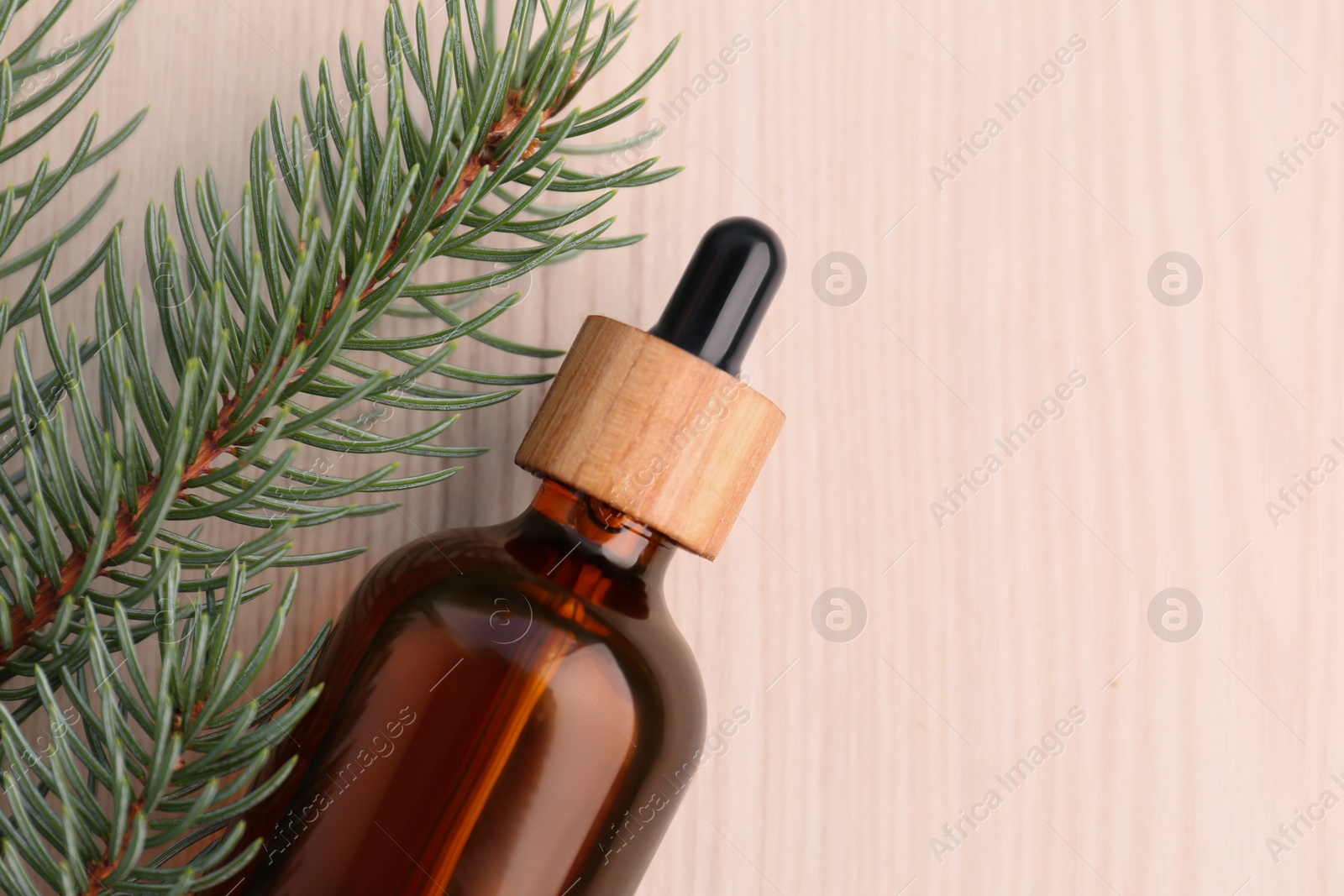 Photo of Pine essential oil and branches on white wooden table, top view. Space for text