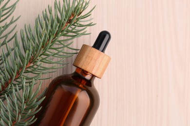 Pine essential oil and branches on white wooden table, top view. Space for text