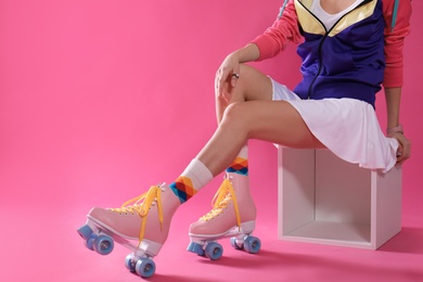 Young woman with retro roller skates on color background, closeup. Space for text