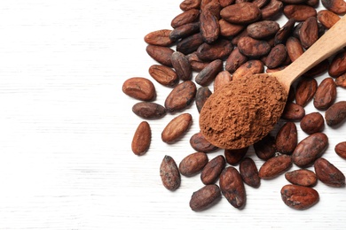 Composition with cocoa beans and powder on white wooden table, above view. Space for text