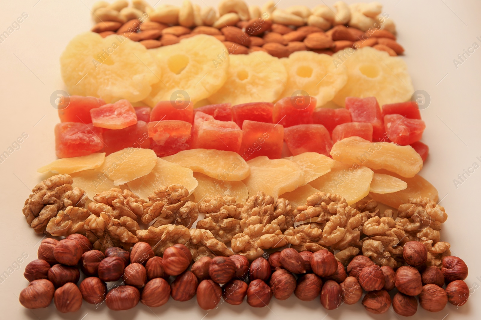 Photo of Different tasty nuts and dried fruits on beige background