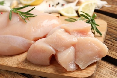 Fresh raw cut chicken breast with rosemary on wooden table, closeup