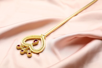 Photo of Beautiful golden magic wand on pink fabric