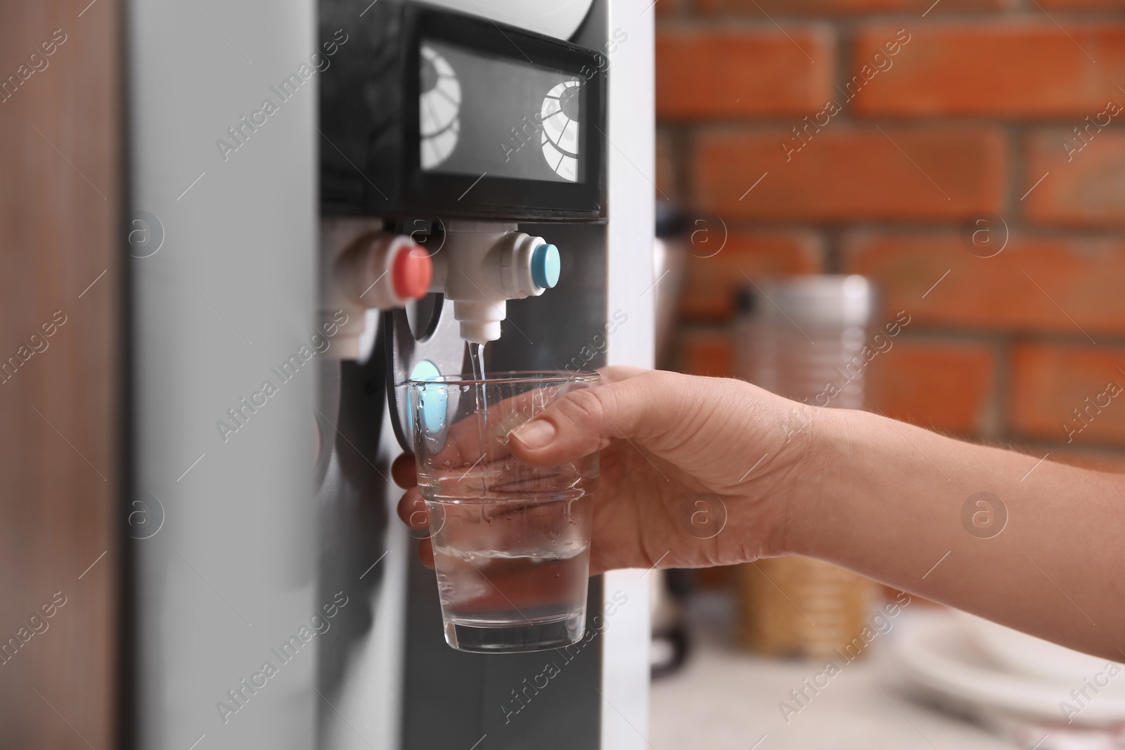 Photo of Woman filling glass with water from cooler indoors, closeup