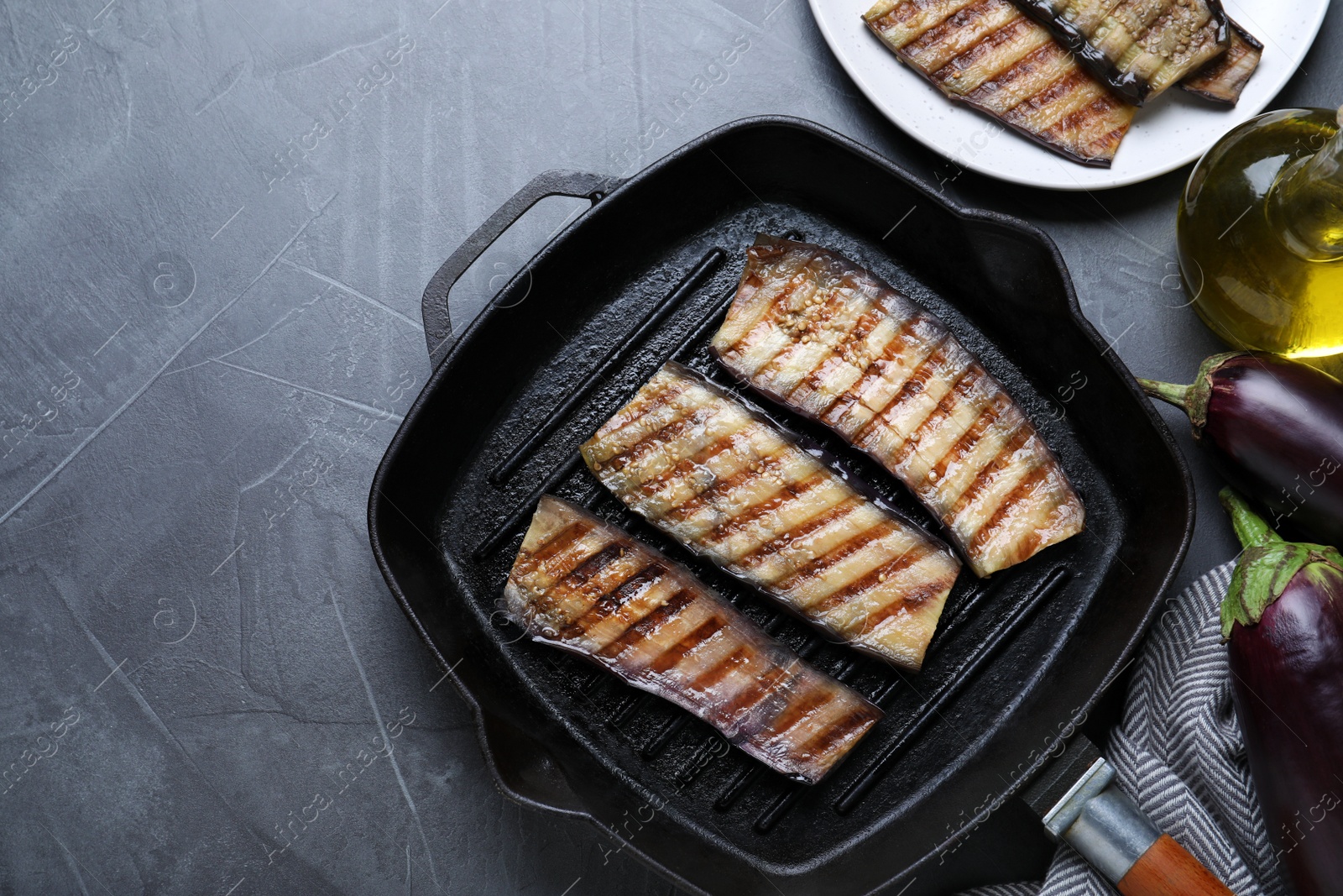 Photo of Delicious grilled eggplant slices in pan on grey table, flat lay