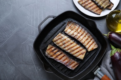 Delicious grilled eggplant slices in pan on grey table, flat lay