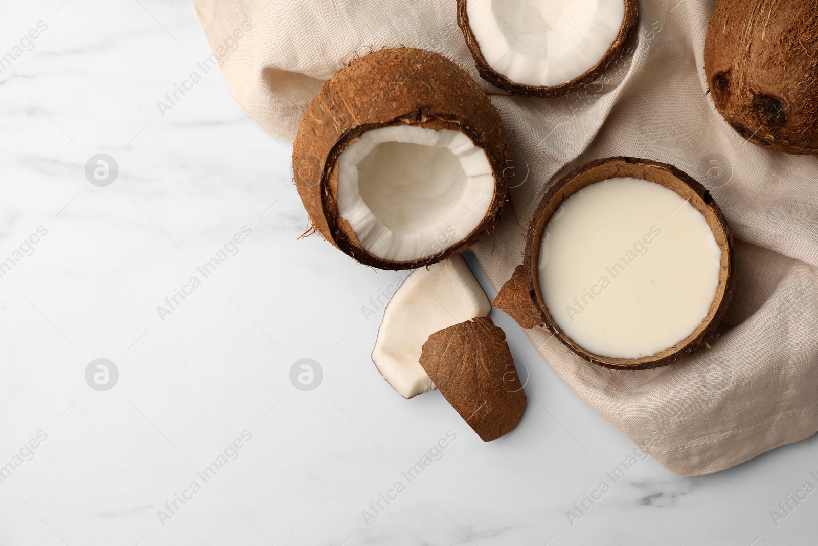 Photo of Delicious vegan milk in coconut and pieces of ripe fruit on white marble table, flat lay. Space for text