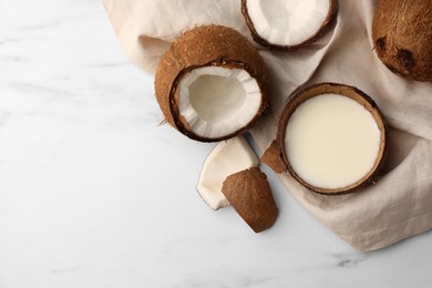 Photo of Delicious vegan milk in coconut and pieces of ripe fruit on white marble table, flat lay. Space for text