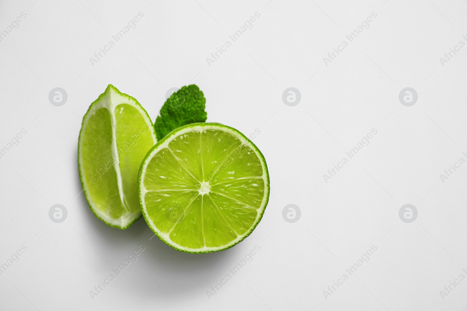 Photo of Cut fresh juicy lime and mint on white background, top view