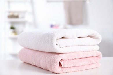 Photo of Stack of fresh towels on table in bathroom