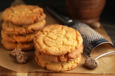 Tasty cookies, nutmeg seeds and grater on wooden board