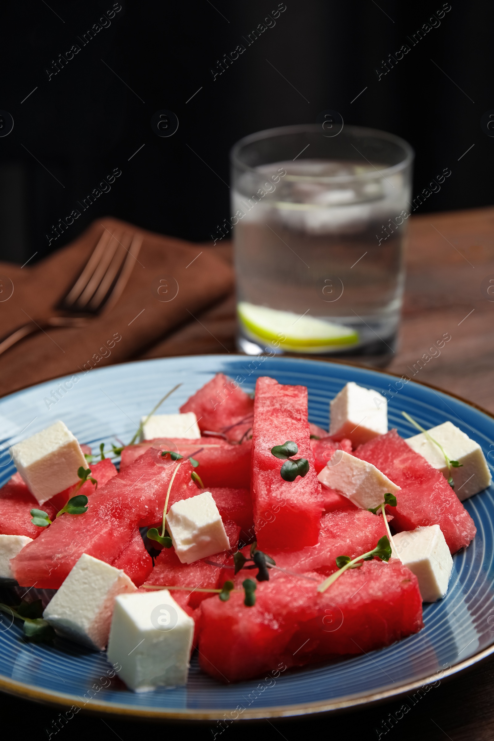 Photo of Delicious salad with watermelon and cheese on wooden table, closeup