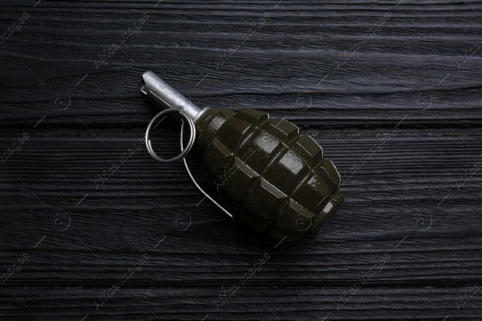 Photo of Hand grenade on black wooden table, top view