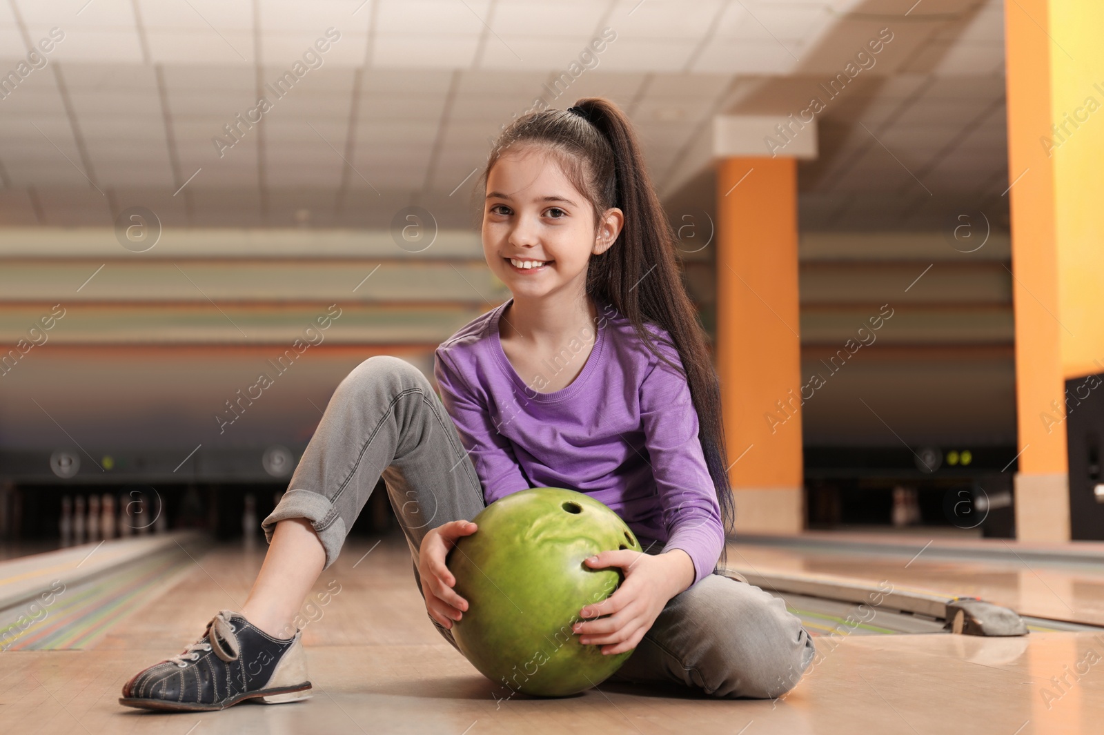 Photo of Little girl with ball in bowling club