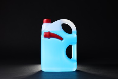 Photo of Plastic canister with blue liquid on black background