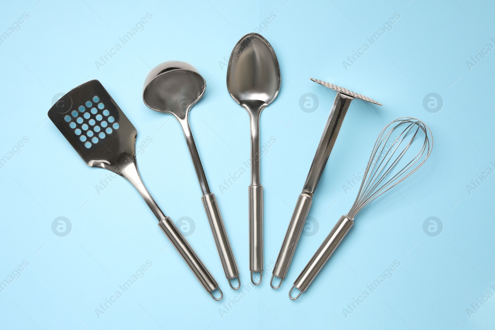 Photo of Set of modern cooking utensils on light blue background, flat lay