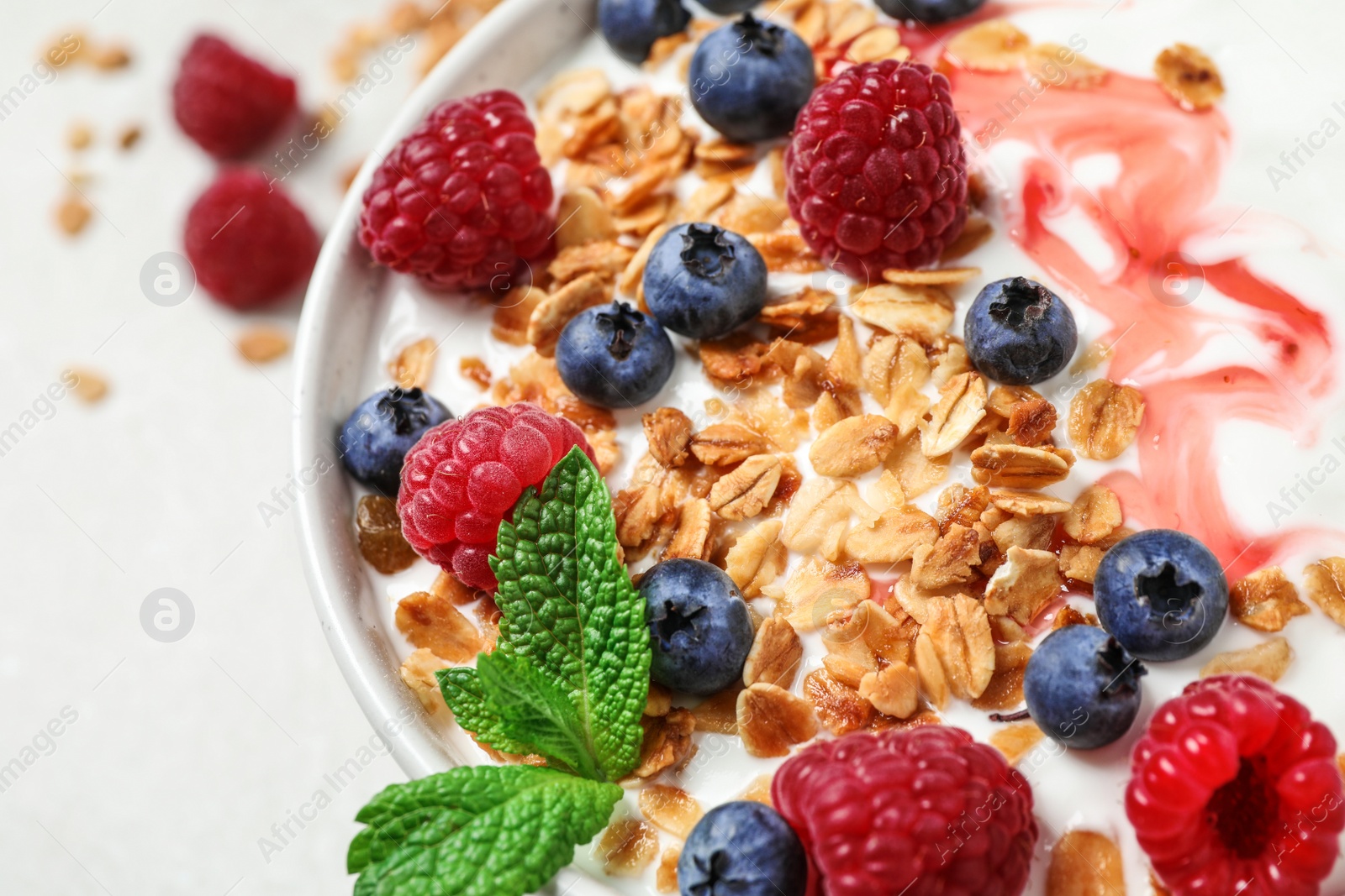 Photo of Tasty homemade granola with yogurt and berries on light table, closeup. Healthy breakfast