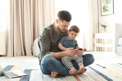 Dad and his son with phone on carpet at home