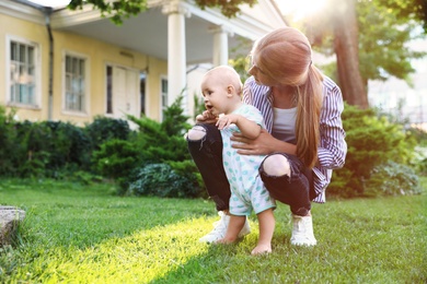 Teen nanny with cute baby on green grass outdoors. Space for text