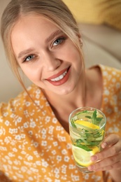 Young woman with glass of lemonade at home. Refreshing drink