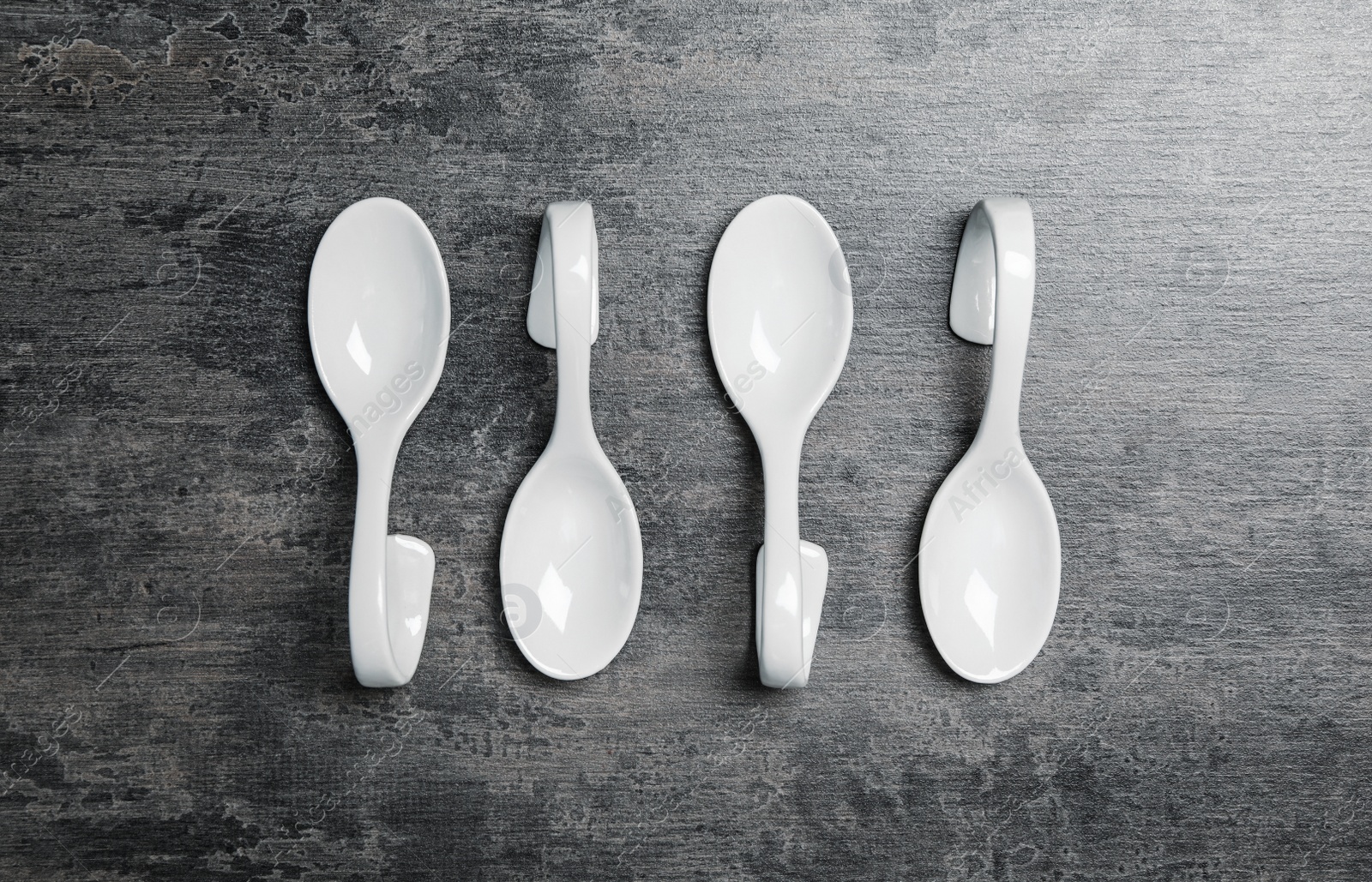 Photo of White spoons on grey table, flat lay. Cooking utensils