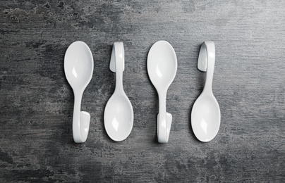 White spoons on grey table, flat lay. Cooking utensils