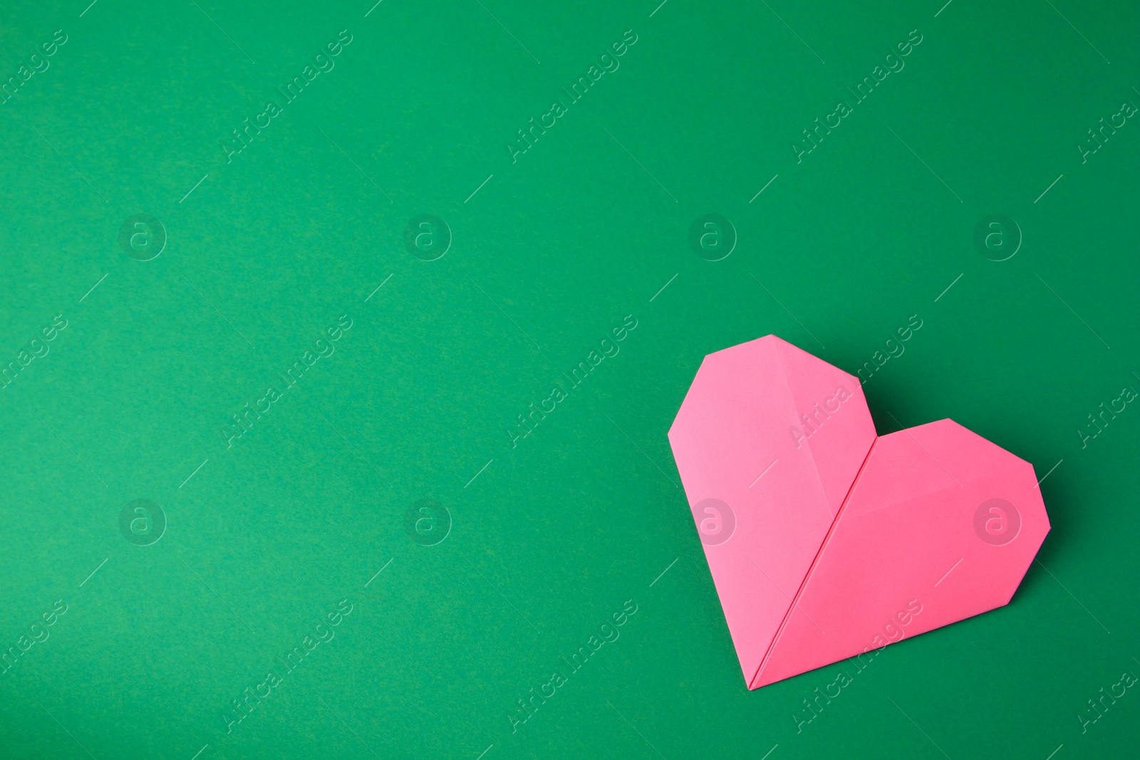Photo of Origami art. Paper heart on green background, top view. Space for text